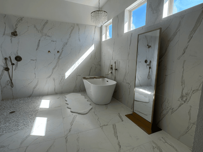 Bright marble bathroom with soaking tub, tall mirror, and windows in Austin, TX home