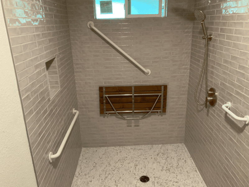 Accessible walk-in shower with grab bars, bench, and tile walls in Austin, TX home