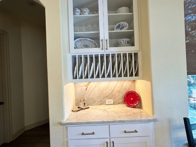 Built-in kitchen hutch with glass cabinets, plate rack, and marble counter in Austin, TX home