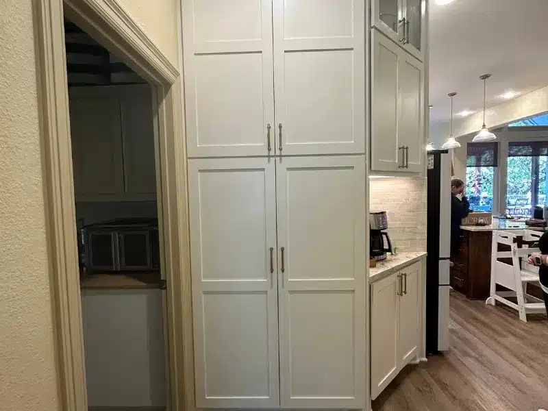 Tall white kitchen cabinets with pantry and coffee nook beside open living area, Austin, TX home<br />

